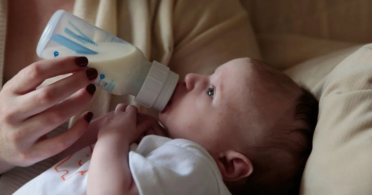 adult feeding a baby with a baby bottle